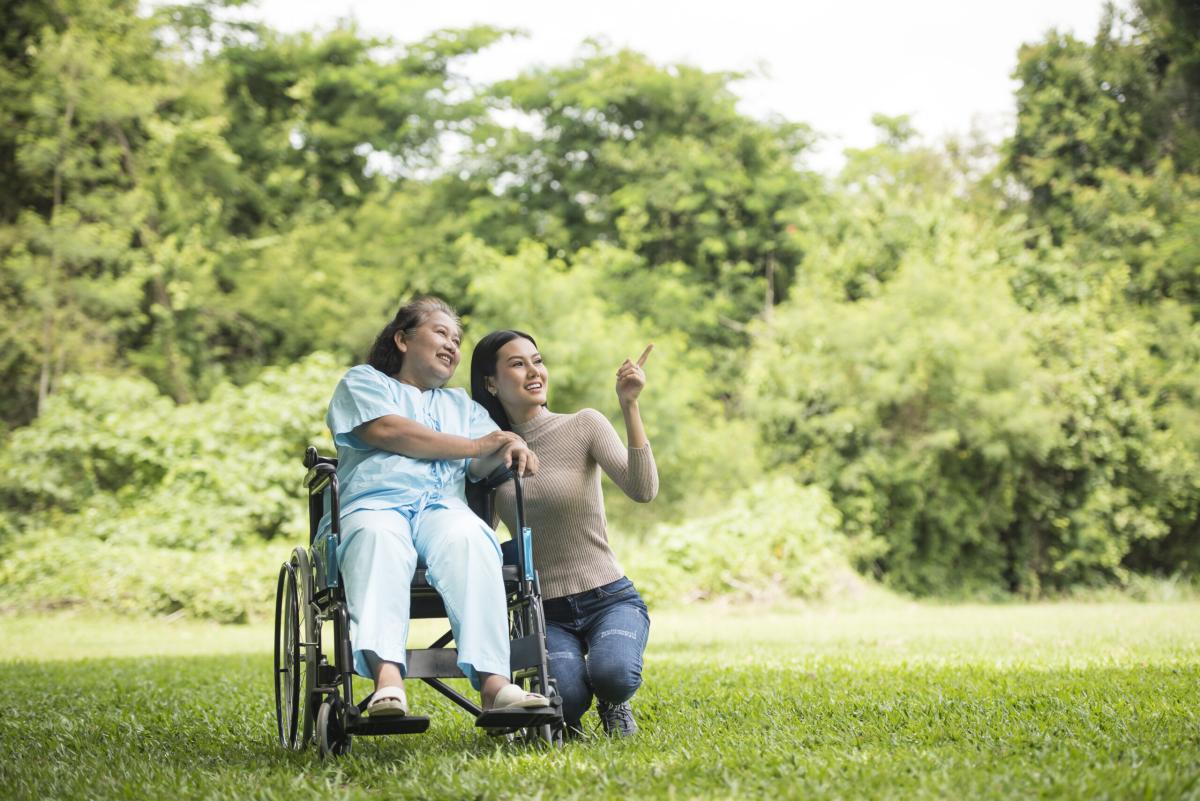 Granddaughter talking with her grandmother sitting wheelchair cheerful