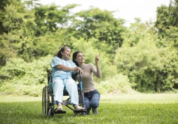Granddaughter talking with her grandmother sitting wheelchair cheerful